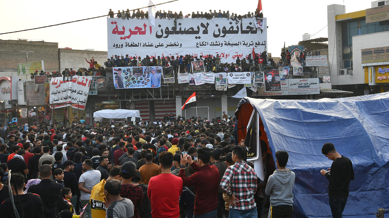 متظاهرون عراقيون أثناء تجمعهم قرب لاقتة كتب عليها 