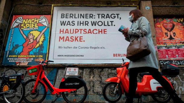 امرأة تمر أمام لافتة تقول بالألمانية: 