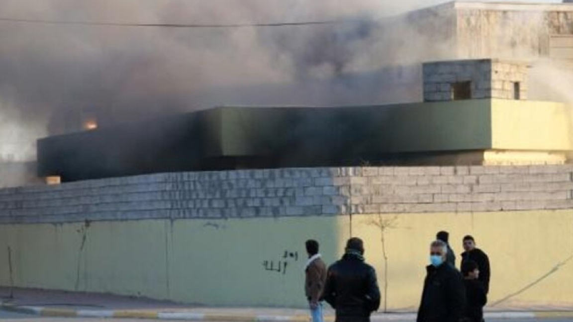 أكراد عراقيون أمام مقر أمني أحرقه متظاهرون في بلدة تكية جنوب غرب محافظة السليمانية الثلاثاء
