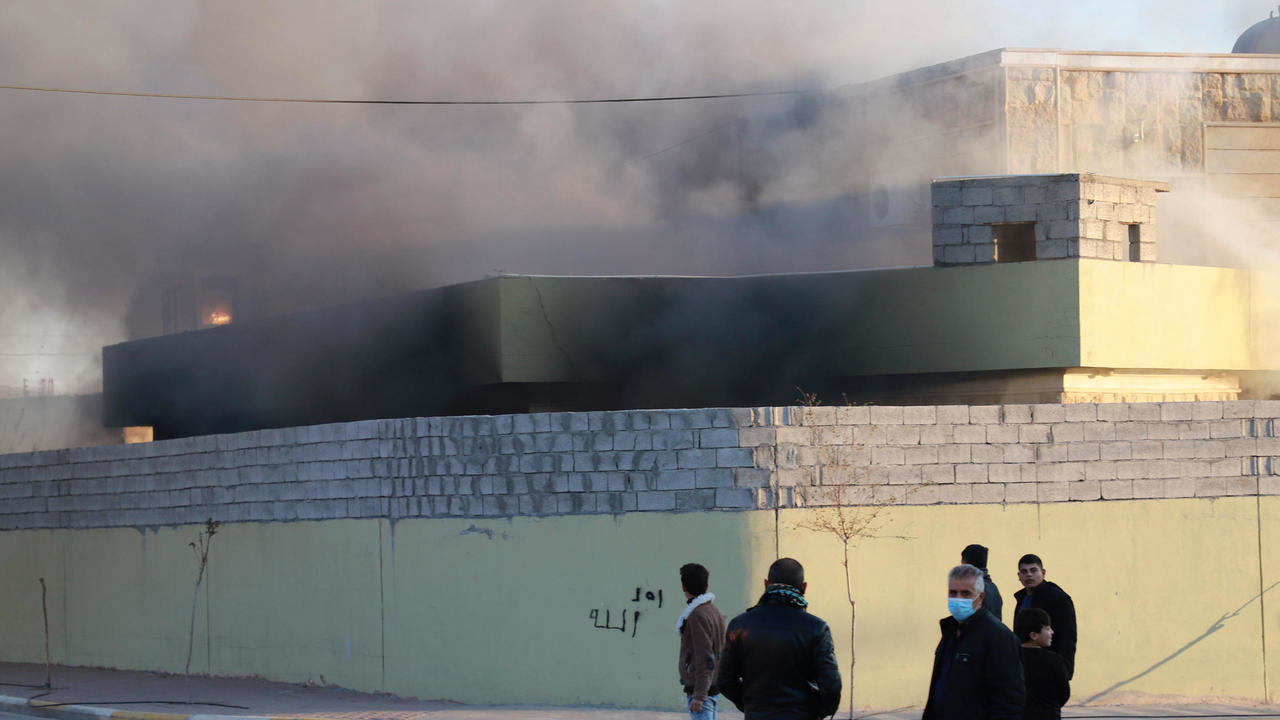 أكراد عراقيون أمام مقر أمني أحرقه متظاهرون في بلدة تكية جنوب غرب محافظة السليمانية بتاريخ 8 كانون الأول/ديسمبر 2020