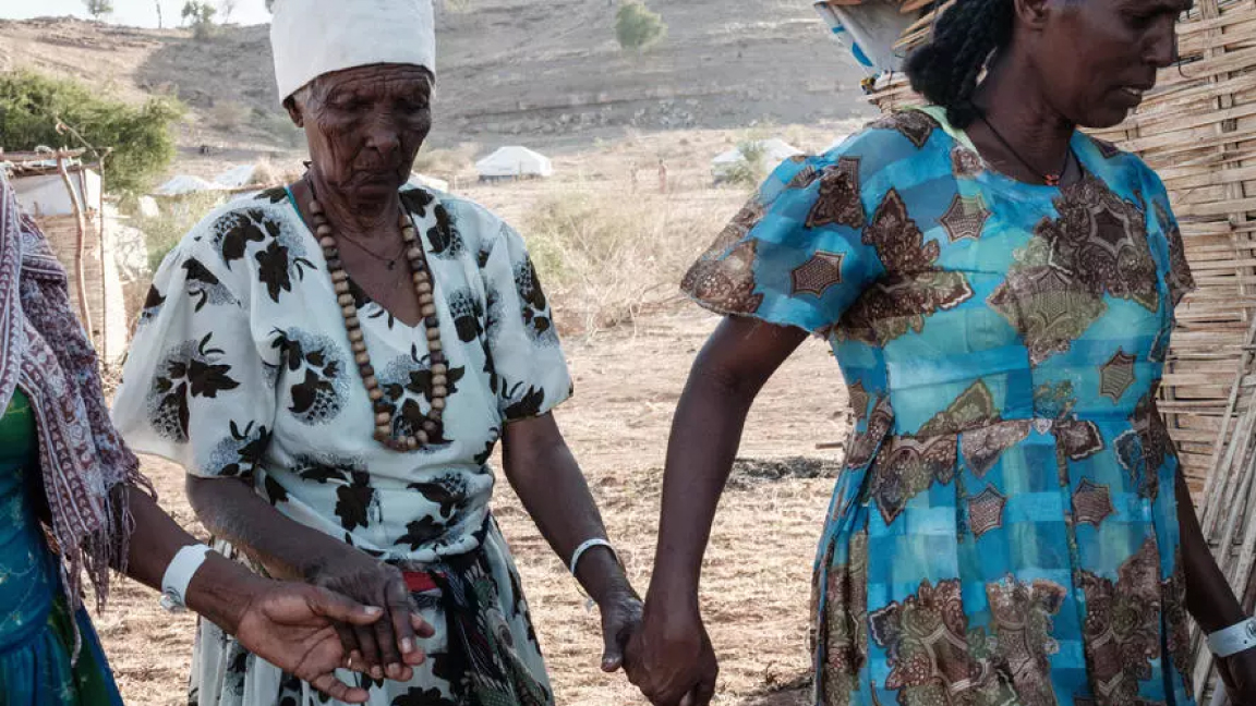 أسافو ألمايا اللاجئة الإثيوبية الثمانينية الضريرة تتلقى مساعدة بناتها في مخيم أم راكوبة في شرق السودان للفارين من منطقة تيغراي السبت