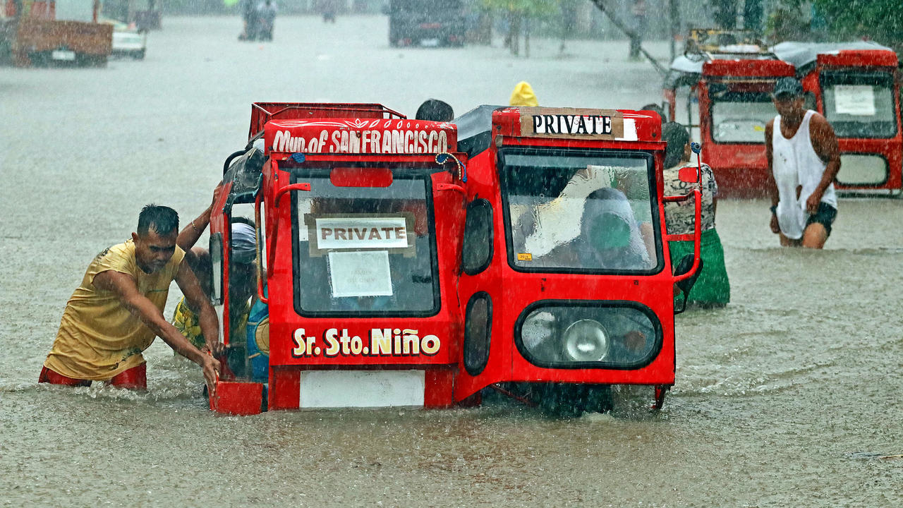 أشخاص يجرون عربة في شارع غرق جرّاء الأمطار الغزيرة في مينداناو في الفيليبين بتاريخ 18 كانون الاول/ديسمبر 2020