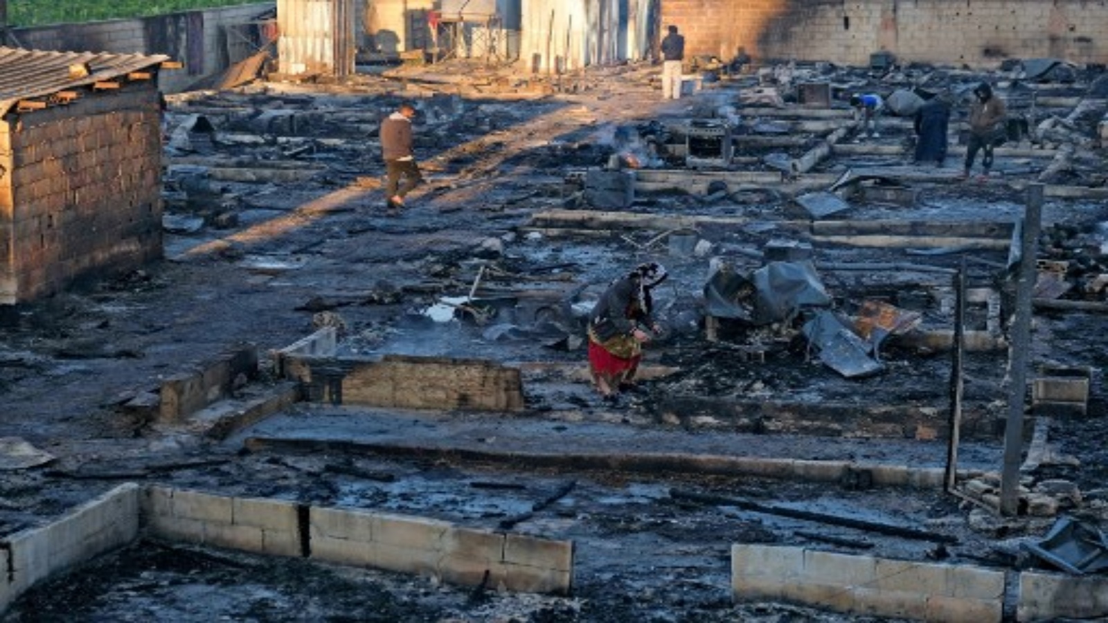 لاجئون سوريون ينتشلون ممتلكاتهم من حطام مآويهم في مخيم أضرمت فيه النيران ليلاً في بلدة بهنين شمال لبنان في 27 ديسمبر 2020 ، بعد مشاجرة بين أفراد المخيم وعائلة لبنانية محلي