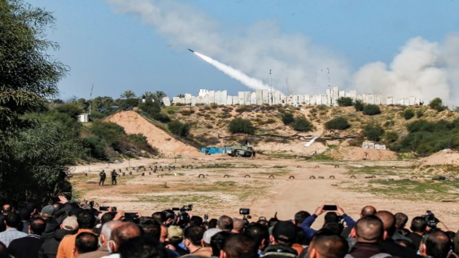 أناس يشاهدون إطلاق صواريخ خلال مناورة عسكرية لحركة حماس الإسلامية الفلسطينية وفصائل فلسطينية مسلحة أخرى في مدينة غزة ، 29 ديسمبر ، 2020.
