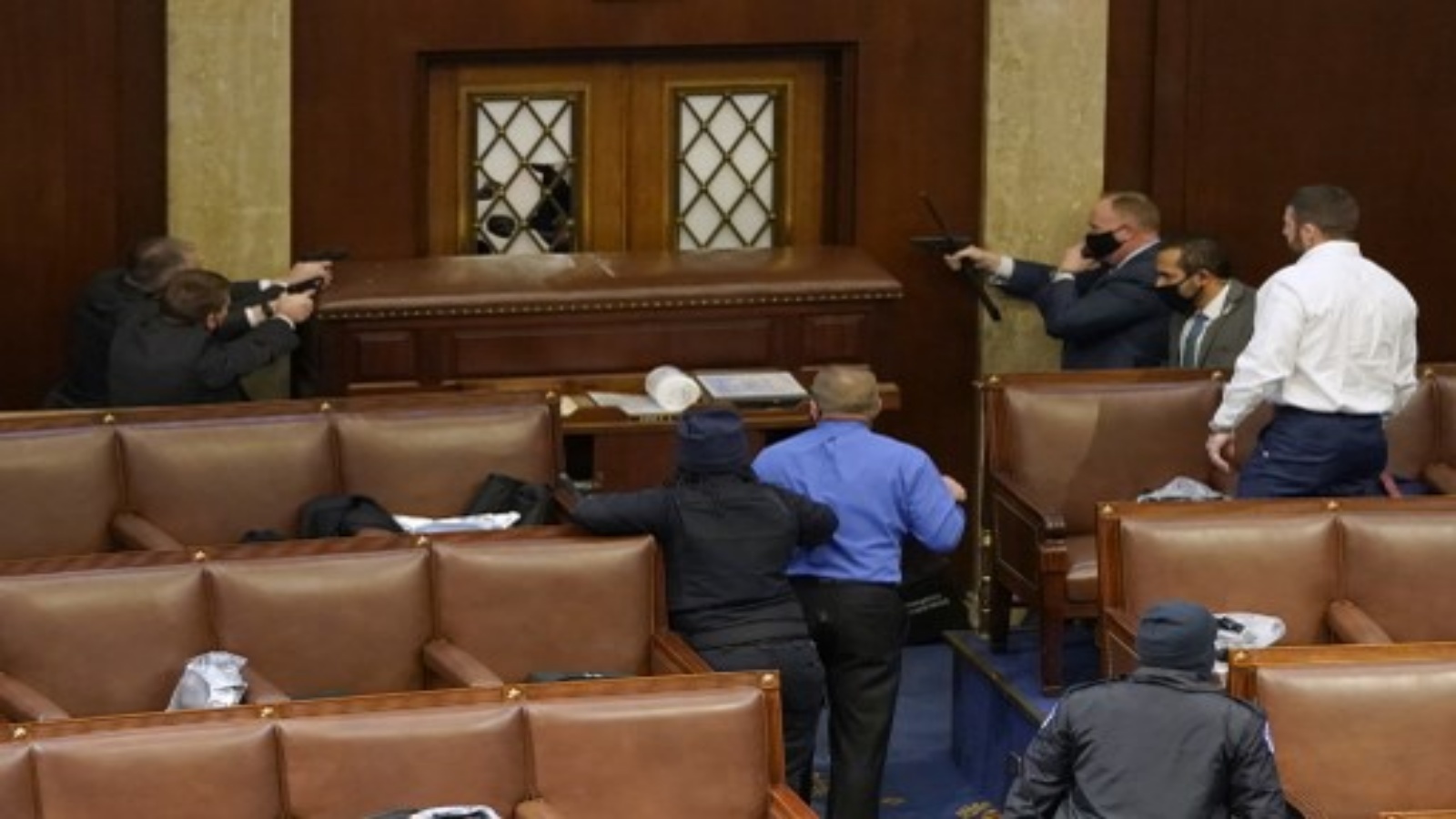 ضباط شرطة الكابيتول يصوبون أسلحتهم على باب تعرض للتخريب في غرفة مجلس النواب خلال جلسة مشتركة للكونغرس في 6 يناير 2021 في واشنطن العاصمة