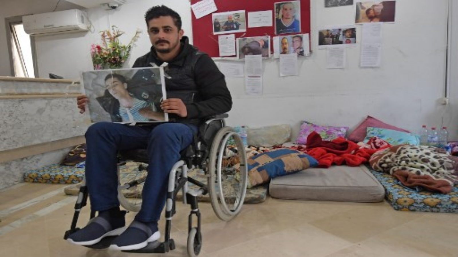 راشد العربي ، 30 عاما ، يحمل صورته بعد إصابته بعيار ناري في يناير 2011 ، حيث بدأ إضرابا عن الطعام في 