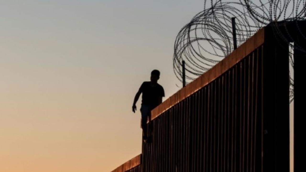 رجل يقف على جزء من الجدار الحدودي بين الولايات المتحدة والمكسيك في بلاياس دي تيخوانا بشمال غرب المكسيك- 18 نوفمبر/تشرين الثاني 2018