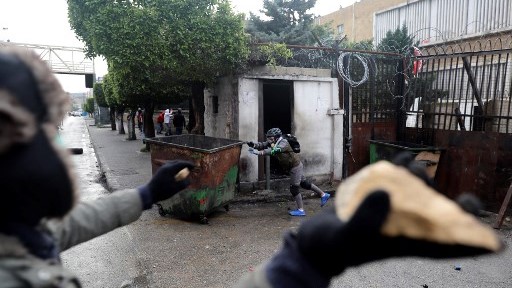 متظاهر يرمي عناصر الشرطة في سراي طلاابلس بالحجارة خلال الصدامات التي جرت الخميس