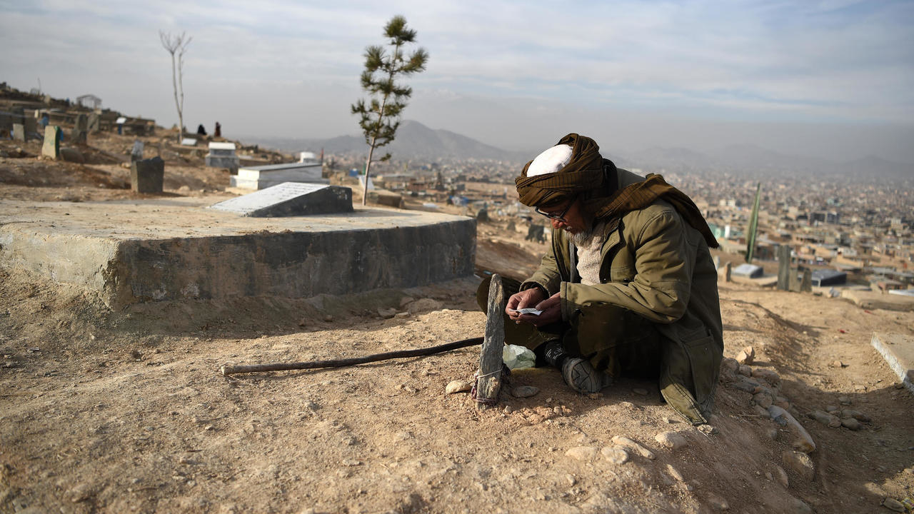 رجل من الهزارة يقرأ القرآن قرب قبر قريب له في محيط كابول في 14 كانون الثاني/يناير 2021