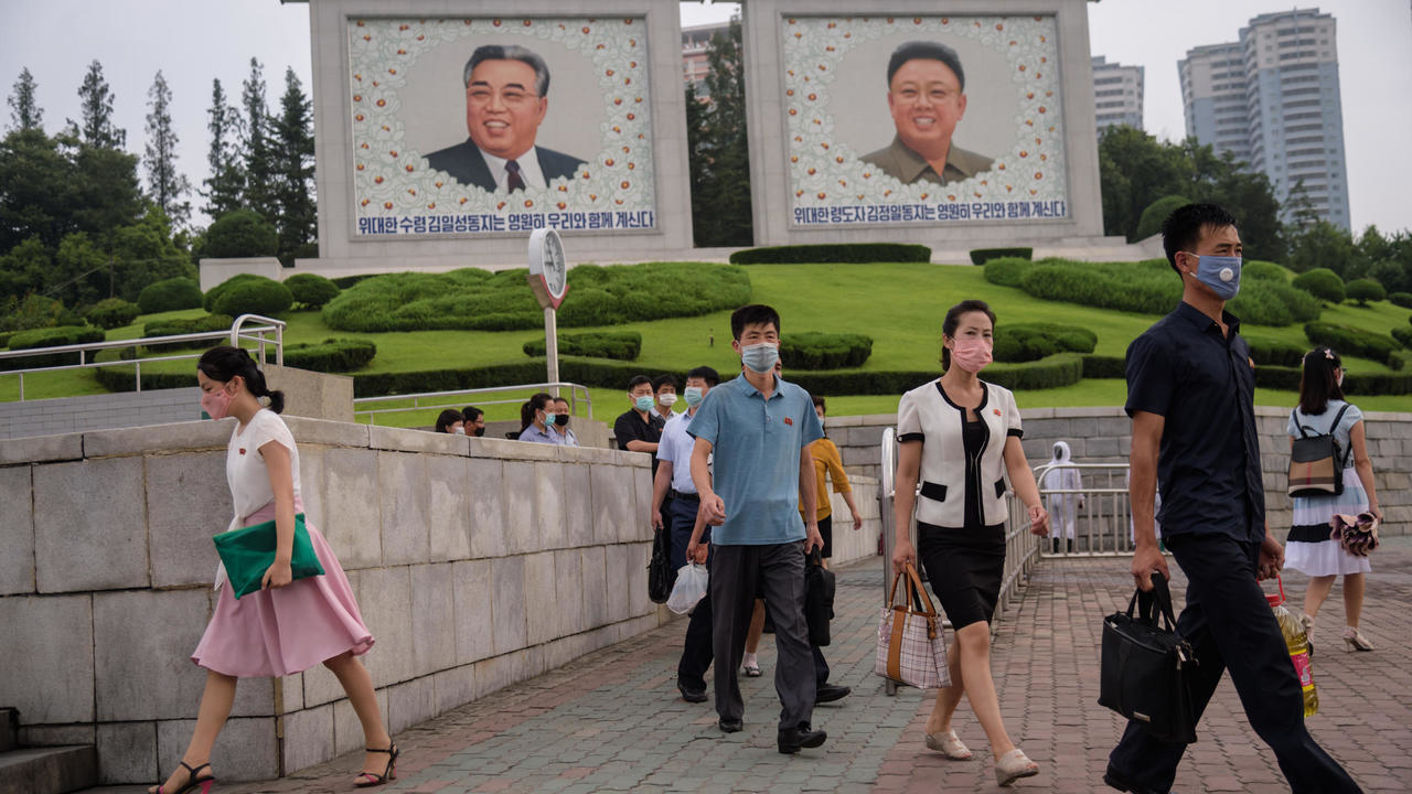 عدد من المارة وفي الخلفية صور الزعيمين الكوريين الشماليين الراحلين كيم ايل سونغ وكيم جونغ ايل في وسط بيونغ يانغ في 19 أغسطس/آب 2020