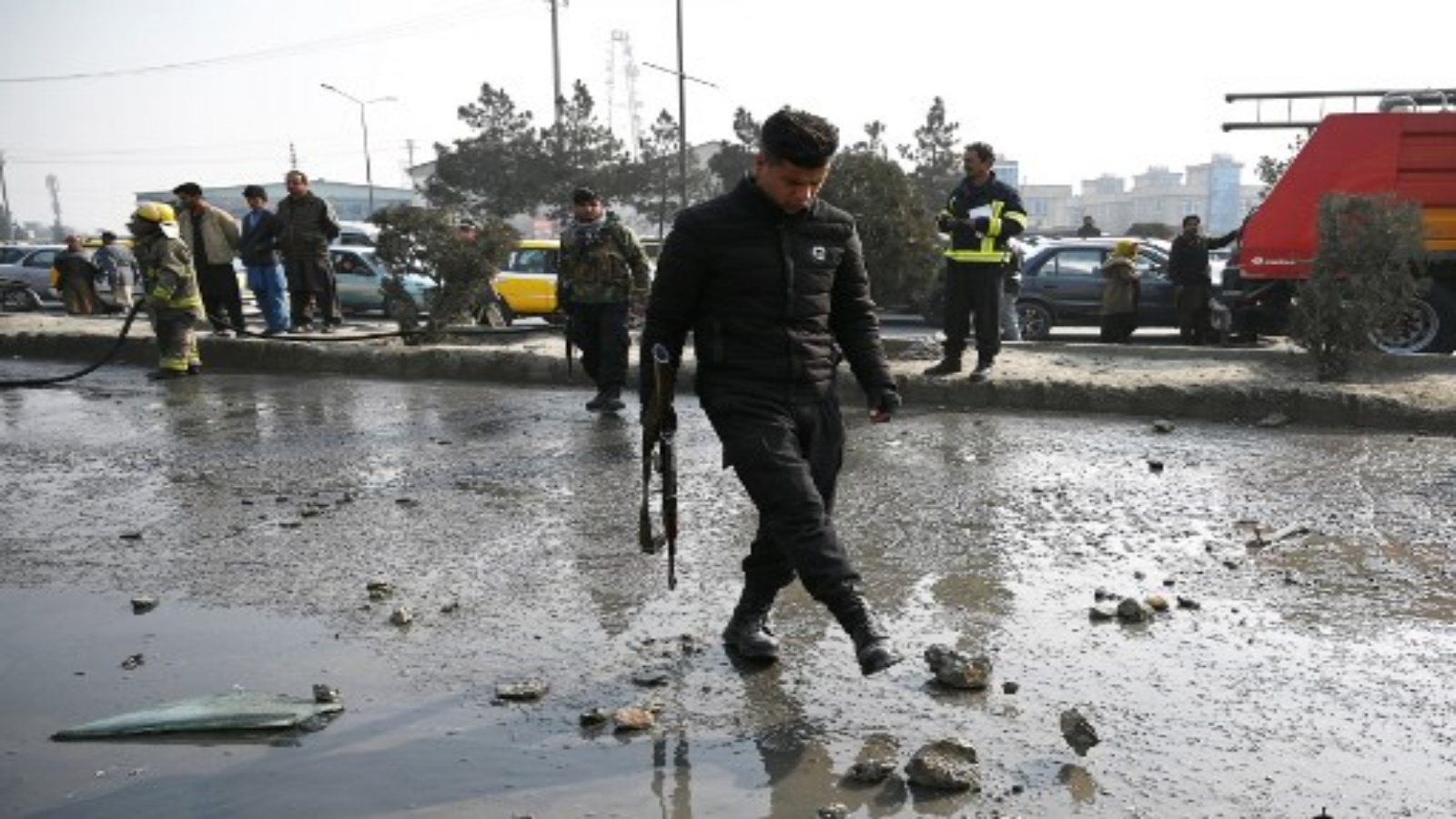 رجل شرطة يتفقد بينما يغسل رجال الإطفاء موقع انفجار قنبلة في كابول في 2 فبراير 2021. قتل شخصان عندما تعرضت العاصمة الأفغانية في 2 فبراير لسلسلة من السيارات المفخخة في ساعة الذروة ، حسبما قال مسؤولون ، بينما قال مسؤولون في الشرطة استهداف سيارة في هجوم شمال كابول.