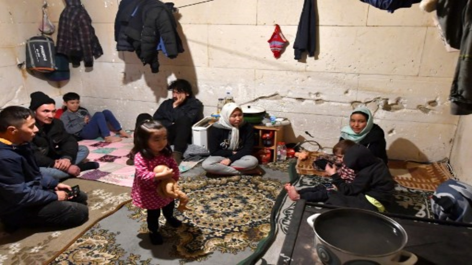 أفراد من ثلاث عائلات مهاجرة ، من أصل أفغاني ، يجتمعون في غرفة في منزل مهجور في 30 يناير 2021 على بعد مئات الأمتار من حدود البوسنة / كرواتيا في قرية بوسانسكا بوجنا الواقعة في شمال البوسنة