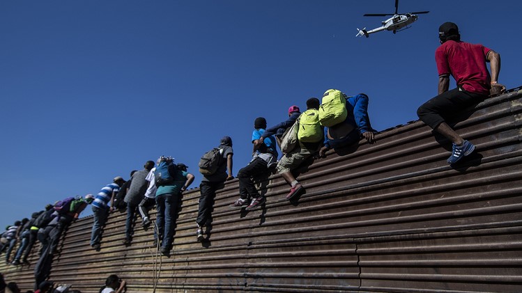 مكسيكيون يتسلقون سياجًا حدوديًا مع الولايات المتحدة للدخول إلى أراضيها
