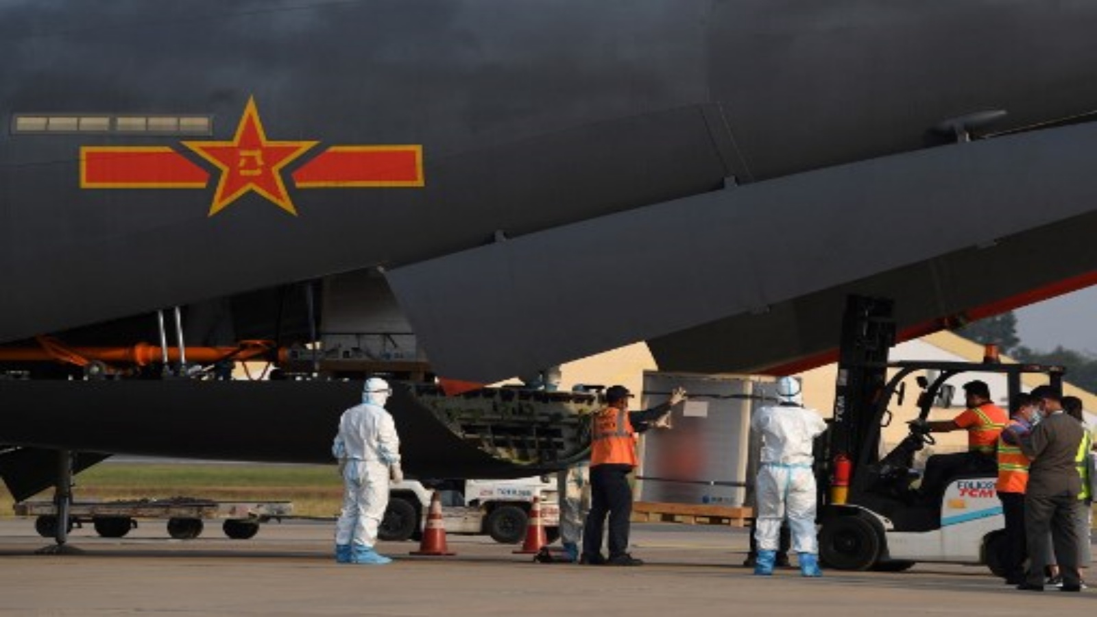 مال ينقلون شحنة من لقاح فيروس كورونا Sinopharm Covid-19 من طائرة عسكرية صينية في مطار بنوم بنه الدولي في بنوم بنه في 7 فبراير 2021