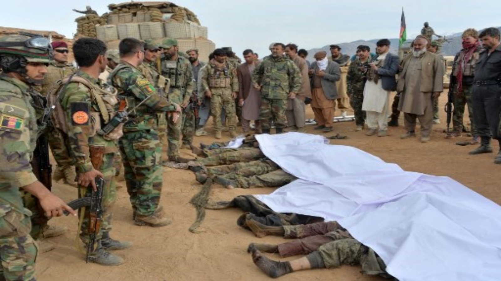 قوات أمن أفغان تتجمع حول جثث مقاتلي طالبان الذين قُتلوا أثناء القتال والغارات الجوية ، في منطقة خوجياني بمحافظة ننكرهار في 12 فبراير 2021.