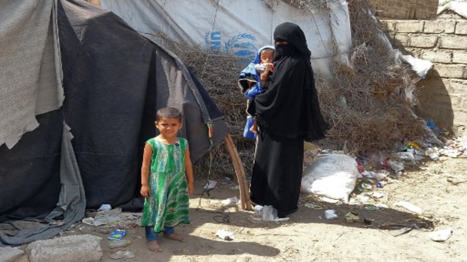 امرأة يمنية نزحت بسبب النزاع تحمل ابنها البالغ من العمر عامين وثمانية أشهر ، ويزن خمسة كيلوغرامات فقط ، بينما تنتظر خارج مأوى للنازحين في محافظة الحديدة الغربية التي مزقتها الحرب ، في 15 فبراير 2021.
