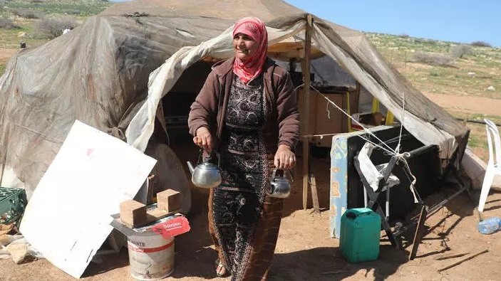بدوية تقف أمام خيمتها في بلدة حمصة في الضفة الغربية المحتلة في 14 فبراير 2021