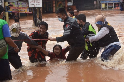 أفراد الإنقاذ يساعدون السكان المتضررين من الفيضانات في بيكاسي ، جاوة الغربية ، في 20 فبراير 2021 ، بعد هطول أمطار غزيرة خلال الليل.