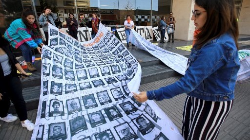 متظاهرة كولومبية تحمل صورة جماعية مركبة من صور ضحايا قتلهم الجيش الكولومبي وقال إنهم لقوا حتفهم في معارك حصلت بين عامي 2002 و2008