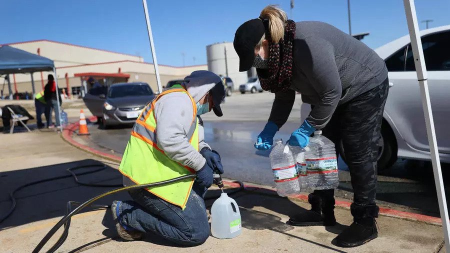 أشخاص يملؤون عبوات مياه في مركز لتوزيع الماء في تكساس السبت