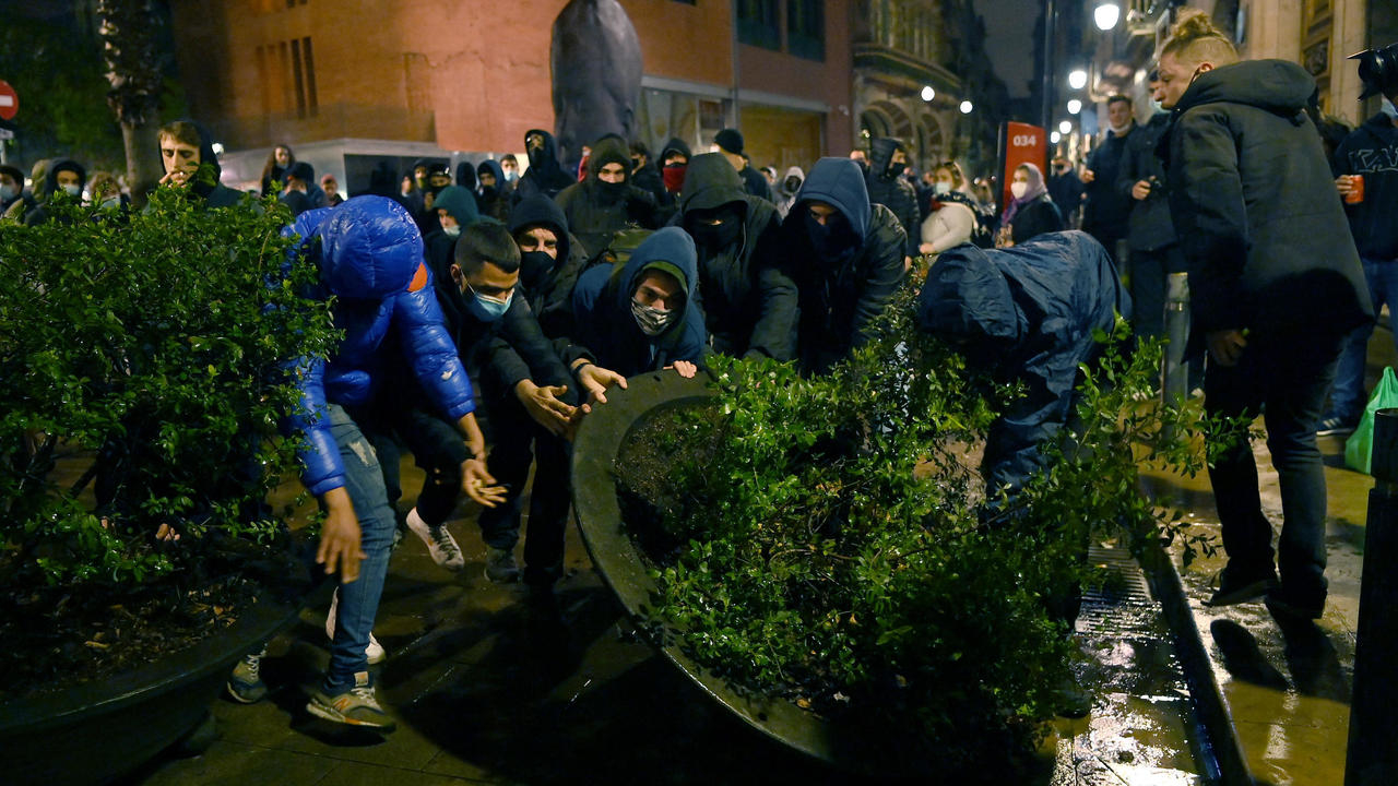 متظاهرون يدفعون حوض شتول ضخما أمام مقر الشرطة الرئيسي في برشلونة مساء 22 فبراير 2021