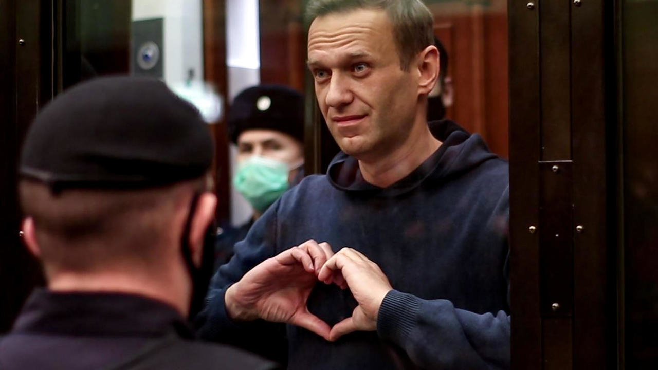 المعارض الروسي أليكسي نافالني في قفص زجاجي أثناء جلسة محاكمة في موسكو، يجمع يديه بشكل قلب، في 2 شباط/فبراير 2021 في صورة وزعها مكتب الإعلام في محكمة موسكو
