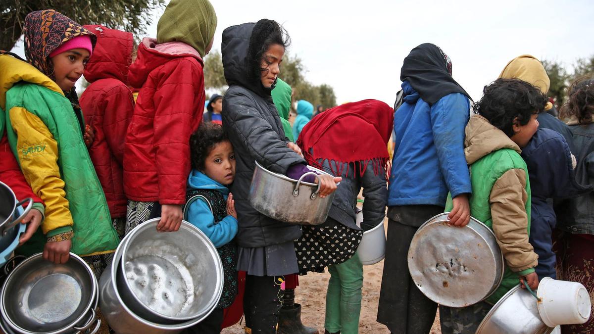 سوريون ينتظرون لتلقي مساعدات غذائية في أحد المخيمات في الشمال السوري