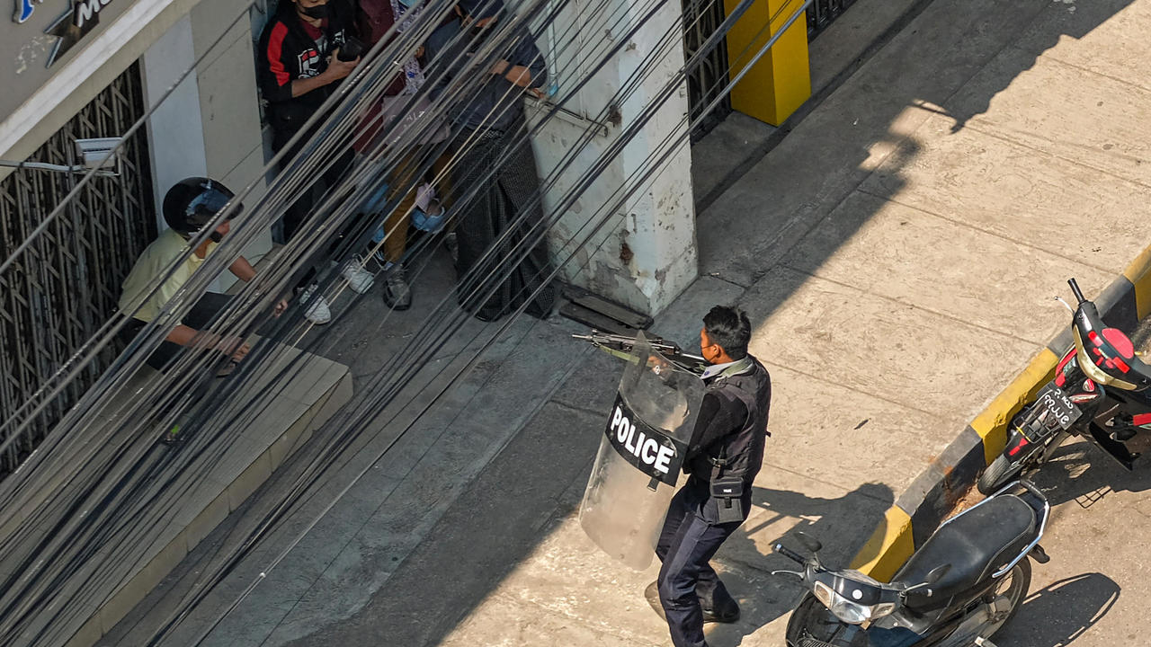 صورة مؤرخة في 28 شباط/فبراير 2021 تظهر شرطيا يشهر سلاحا في وجه متظاهرين في ولاية شان البورمية