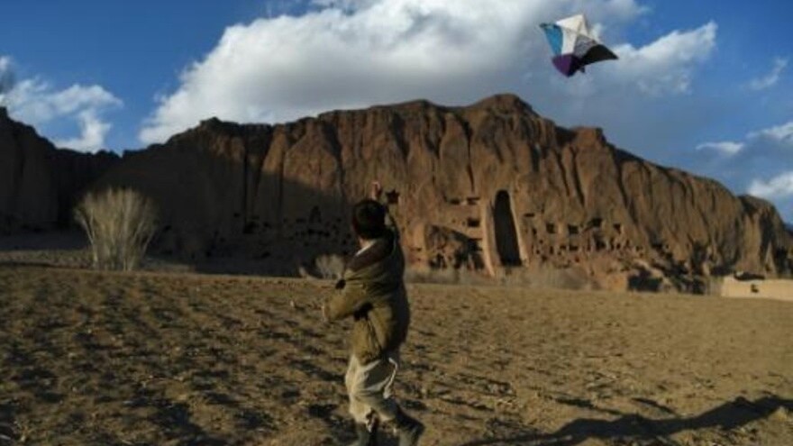 صبي من اتنية هزارة يلهو بطائرة ورقية قرب مواقع تماثيل بوذا الضخمة التي فجرتها حركة طالبان في 2001، في وادي باميان في أفغانستان في 3 مارس 2021