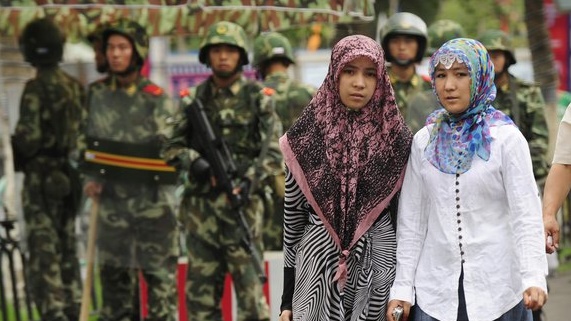 فتاتان من الأويغور تمران بجانب رجال الشرطة الصينية
