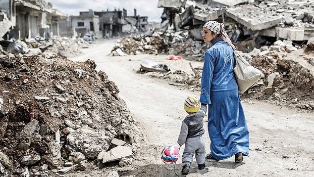 سيدة كردية تمر بحي مدمر في كوباني