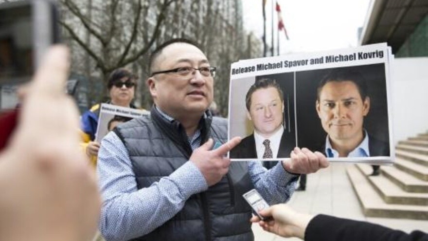 لويس هوانغ من منظمة فانكوفر للحرية والديموقراطية يحمل صورتي الكنديين مايكل سبافور ومايكل كوفريغ في 06 مارس 2019