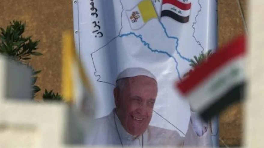 صورة البابا وأعلام العراق أمام كاتدرائية القديس يوسف في وسط بغداد في 10 مارس 2021