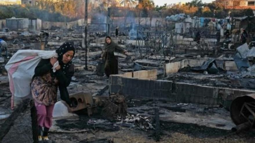 لاجئة سورية تحمل مقتنيات جمعتها من خيمتها في 27 كانون الأول/ديسمبر 2020 غداة إضرام النيران في مخيم للاجئين في شمال لبنان على خلفية إشكال بين عدد من قاطني المخيم ولبنانيين