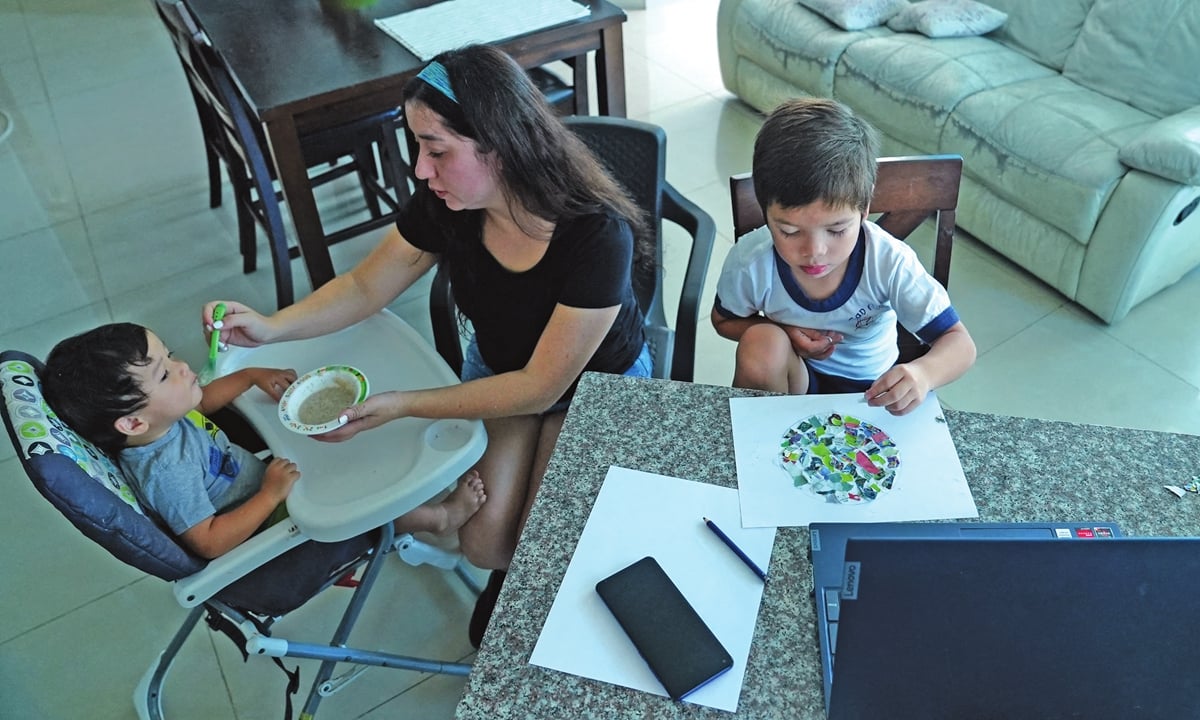 رافاييل (5 سنوات) يشارك في فصوله الافتراضية بينما والدته آنا (33 عامًا) تطعم ابنها الآخر في مدينة بنما