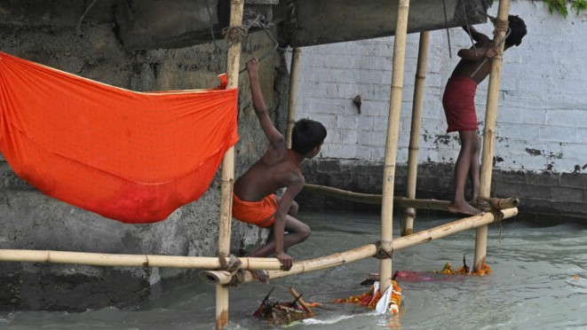 فتيان يستعدان للنزول في نهر الغانج بحثا عن تقديمات رماها حجاج في المياه خلال نزولهم للتطهر في 12 مارس 2021 في هاريدوار شمال الهند