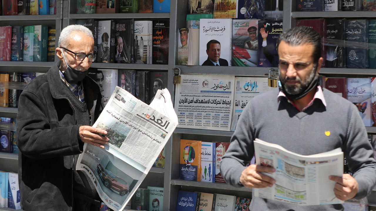 أردنيون يقرأون الصحف المحلية وعلى صحفاتها الأولى أحداث اعتقالات الأمس، أمام كشك في العاصمة عمان في 4 نيسان/أبريل 2021
