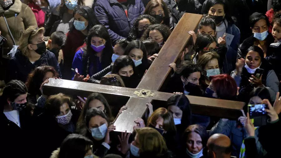 مسيحيون يحملون صليبًا خشبيًا لدى وصولهم إلى كنيسة القيامة بعد أن ساروا على درب الآلام في بلدة القدس القديمة في يوم الجمعة العظيمة في 2 أبريل 2021