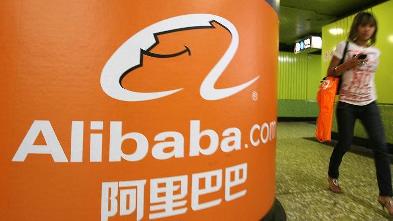 صينية تمر أمام شعار موقع علي بابا للبيع بالتجزئة على الإنترنت
