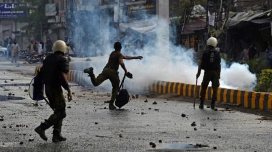 شرطي يرشق أنصار حركة لبيك باكستان بالحجارة خلال تظاهرة في لاهور بعد توقيف زعيم الحركة الذي دعا إلى طرد السفير الفرنسي في 12 أبريل 2021