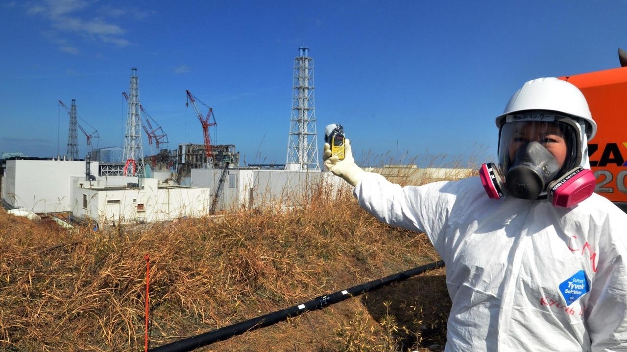 صورة لصحفية تتحقق من مستويات الإشعاع باستخدام مقياس الجرعات الخاص بها بجوار محطة فوكوشيما دايتشي للطاقة النووية المنكوبة في مدينة أوكوما بمحافظة فوكوشيما