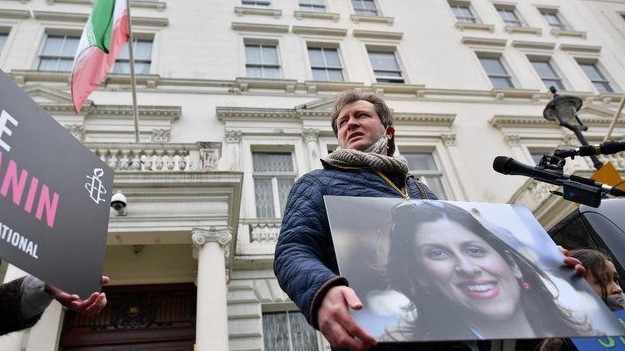 زوج ازنين-زاغري راتكليف يحمل صورتها في تجمع أمام القتصلية الإيرانية في لندن