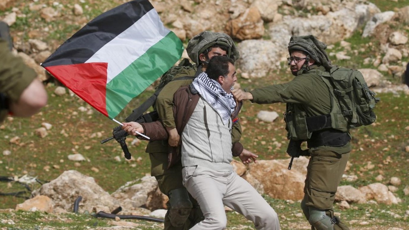 جندي إسرائيلي يحاول صد متظاهر فلسطيني