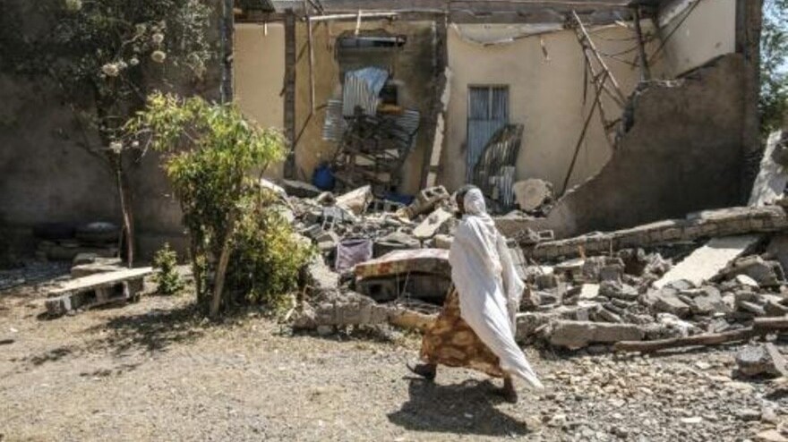 امرأة تمر أمام منزل متضرر في ووكرو نتيجة المعارك بين الجيش الفدرالي الإثيوبي وقوات تيغراي المتمردة بتاريخ الأول من مارس 2021