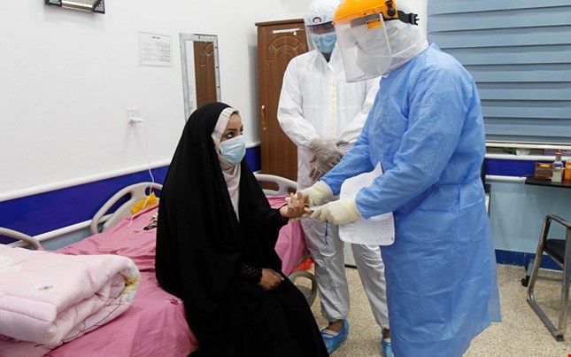 طبيب يفحص عراقية من اصابة بفايروس كورونا