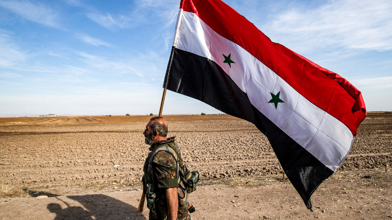 جندي يحمل العلم الرسمي السوري بتاريخ 5 تشرين الثاني/نوفمبر 2019