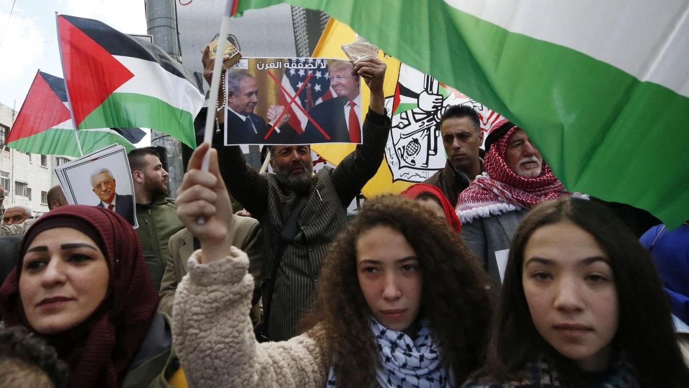 فلسطينيات يلوحن بالأعلام الوطنية أثناء احتجاجهن على اقتراح خطة سلام أميركية في وسط مدينة الخليل بالضفة الغربية. 30 يناير 2020 