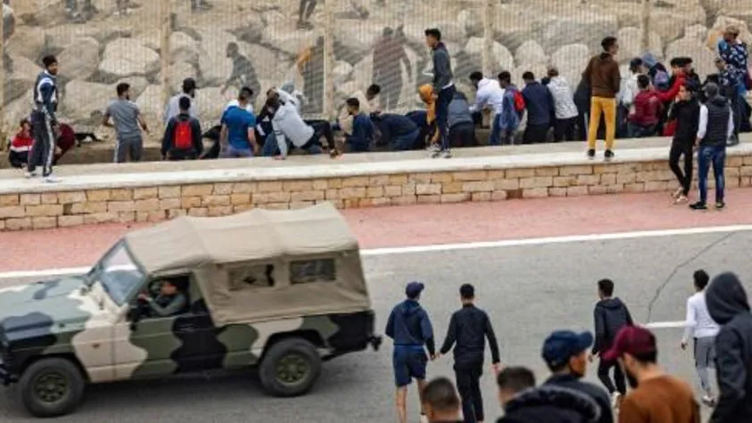سيارة لقوى الأمن المغربية تمر قرب مهاجرين غير قانونيين يريدون الوصول الى جيب سبتة الإسباني 