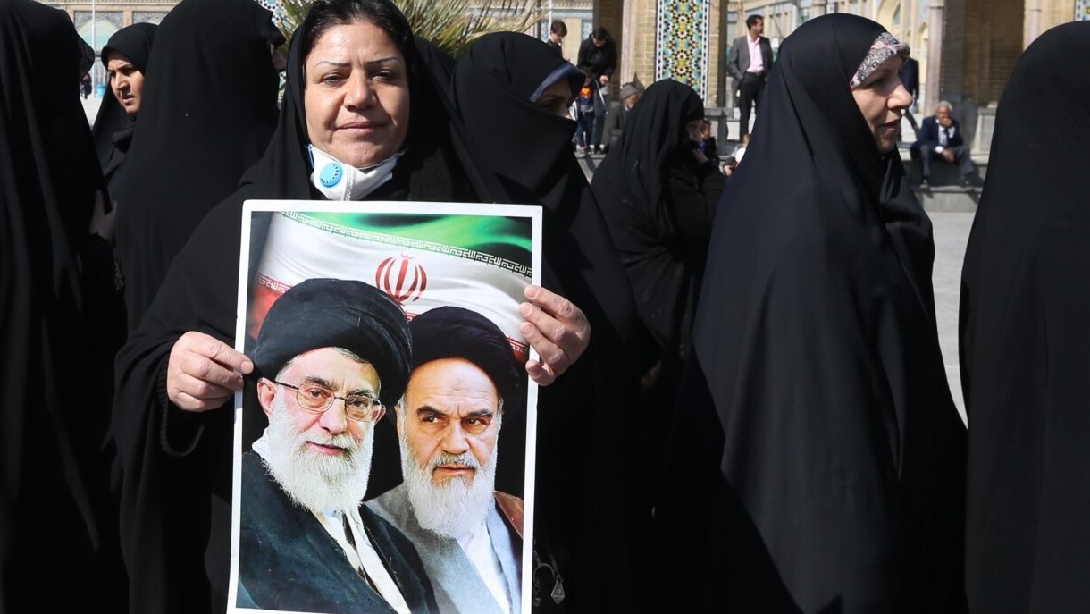 إيرانية تحمل صورة للخميني والخامنئي في طهران