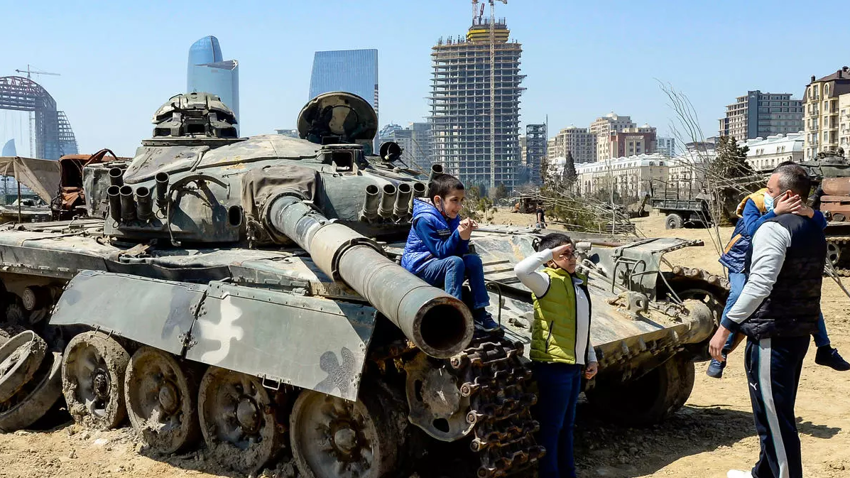 طفل يؤدي التحية العسكرية أمام دبابة خلال زيارة لموقع في باكو 